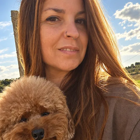 La criadora de Dracarys Poodles con uno de sus caniches, al sol en la finca